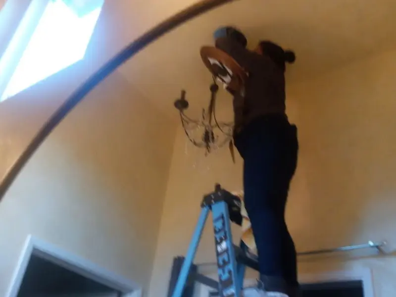 Electrician installing a chandelier in a Paris residence